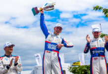 Daniel Lloyd celebrates with a trophy on the podium